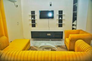 a living room with two yellow couches and a tv at Supreme hosts in Yaoundé