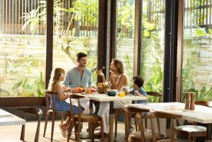 a family sitting at a table in a restaurant at Holiday Inn Resort Bali Canggu by IHG in Canggu
