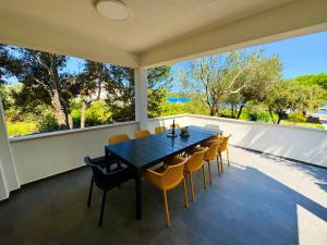 a dining room with a table and chairs on a balcony at Holiday home Prora Mare in Ždrelac