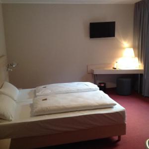 a hotel room with two beds and a tv on the wall at Rasthof & Motel Hermsdorfer Kreuz in Hermsdorf