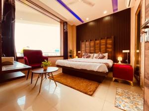 齐拉克普尔Hotel Pearl Grand-Family Hotel-Feel Like home的一间卧室配有一张大床和两张红色椅子