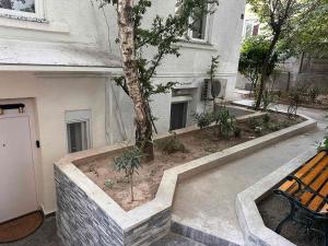 a bench in front of a building with a tree at City Garden Studio Apartment in Belgrade in Belgrade