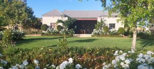 ein großes weißes Haus mit einem Hof mit Blumen in der Unterkunft Ouma Bettie Guesthouse in Piketberg
