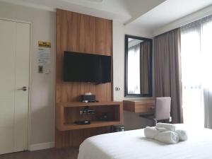 a hotel room with a bed and a flat screen tv at Modern 1BD Executive Suite, Netflix Wifi Pool Gym in Manila