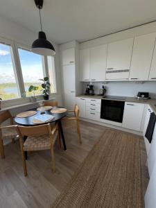 a kitchen with a table and a kitchen with white cabinets at Valoisa kaksio merimaisemalla keskustassa in Vaasa