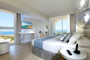 a bedroom with a bed with a view of the ocean at Palladium Hotel Menorca in Arenal d'en Castell