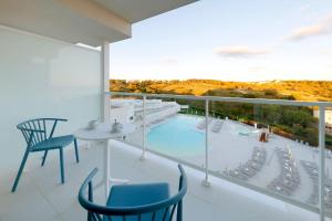 a balcony with a view of a swimming pool and chairs at Palladium Hotel Menorca in Arenal d'en Castell