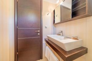 a bathroom with a white sink and a wooden door at Villa Salvia in Katávolos +24 photos