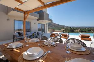 a dining room with a wooden table and chairs at Calmo Luxury Villas, with Pool Tranquil Elegance, By ThinkVilla in Lamerianá +59 photos
