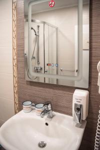 La salle de bains est pourvue d'un lavabo et d'un miroir. dans l'établissement Three Dolphins Hotel with a Rooftop terracе, à Varna 75 autres photos