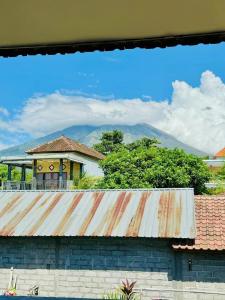a house with a rusty roof with mountains in the background at Shan Hai Jing Hotel in Tulamben