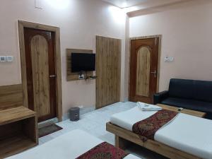 a room with a bed and a couch and a tv at HOTEL SUDAKSHINA by ROH in Silchar