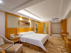a bedroom with a large white bed and a couch at Vienna Hotel Shenzhen Longhua Renmin South Road in Bao'an