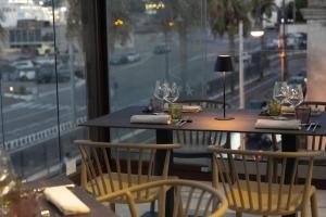 Un restaurante con dos mesas y sillas y una ventana. en Petit Hotel, en Milazzo