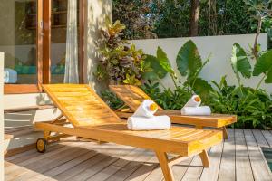 two wooden chairs with towels on them on a porch at Villa Canopy at Nyanyi in Tabanan
