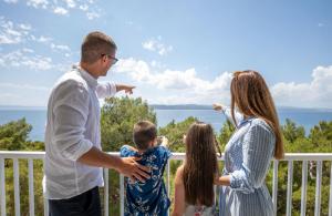 a family standing on a porch looking at the ocean at Bluesun Hotel Marina in Brela