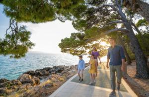 a family walking along a path by the ocean at Bluesun Hotel Marina in Brela