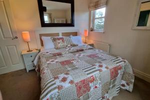 a bedroom with a bed with a quilt on it at Heath House Loch Ness in Errogie