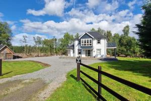 a white house with a fence next to a driveway at Heath House Loch Ness in Errogie
