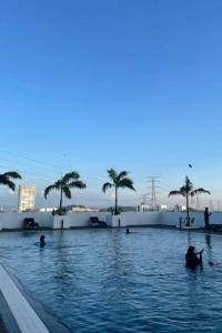 a pool with palm trees and people in the water at Meritus - Perai in Perai