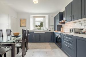 a kitchen with blue cabinets and a sink and a table at Kinness Place - No 6 in St. Andrews
