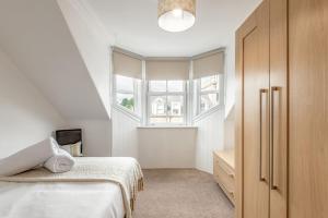 a white bedroom with a bed and a window at Kinness Place - No 6 in St. Andrews