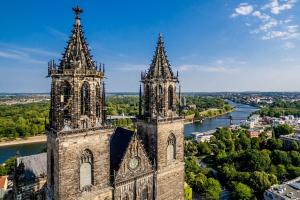 an old church with two towers and a river at City Apartment in Magdeburg