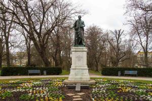 a statue of a man in a park with flowers at City Apartment in Magdeburg