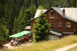 people sitting at tables outside of a wooden building at Horská chata Amor in Pec pod Sněžkou