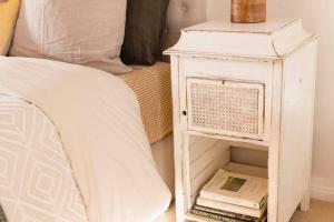 a white nightstand next to a bed with a book at Peony Farm Green Cottage in Stanley