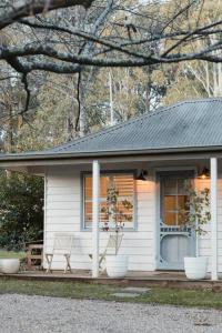 a white house with a bench and two plants at Peony Farm Green Cottage in Stanley +16 photos
