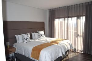 a bedroom with a large bed with a large window at Hururu House in Dullstroom