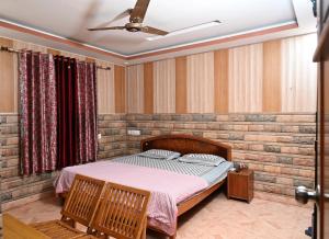 a bedroom with a bed with two chairs and a ceiling fan at Hotel Sunrise in Chandīgarh