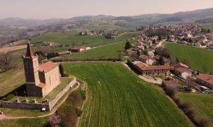 an aerial view of an old church in a green field at Les pierres roses in Coise