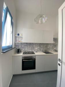 a white kitchen with a stove and a window at Casa n'to strittu in Lipari