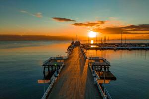 a dock with the sun setting over the water at SeaSide Sopot - butikowe noclegi przy plaży in Sopot