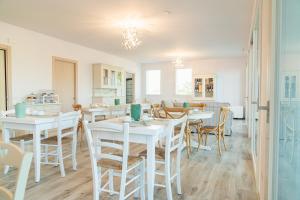 eine Küche und ein Esszimmer mit weißen Tischen und Stühlen in der Unterkunft I Campi Wine Relais in Ronchi