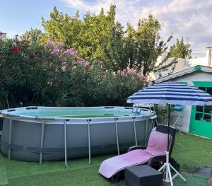 a hot tub in a yard with a chair and an umbrella at Joli studio tout confort avec toutes commodités in Vaulx-en-Velin