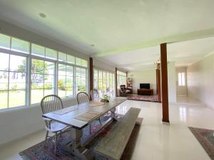 a dining room with a table and chairs and windows at Super Wonderful 5 bedrooms with Bathroom Villa Marion Tomohon in Tomohon