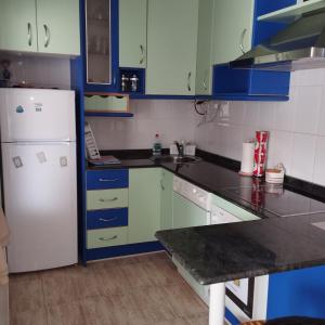 a kitchen with a white refrigerator and blue cabinets at Atico en Ajo Cantabria in Ajo +13 photos