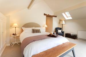 ein Schlafzimmer mit einem großen weißen Bett und einem Stuhl in der Unterkunft Rocking Stone Cottage in Matlock