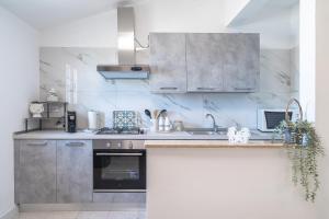 una cocina con armarios de acero inoxidable y fregadero en Ferienwohnung Villa Segesta, en Siracusa