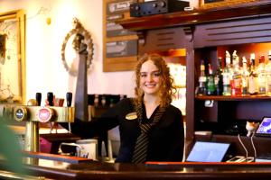 a woman standing behind a bar in a pub at City Hotel Restaurant Stadskanaal in Stadskanaal