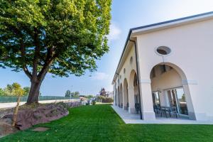 Ein weißes Gebäude mit einem Baum daneben. in der Unterkunft I Campi Wine Relais in Ronchi