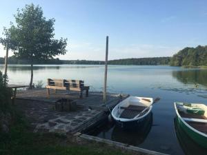 a wooden dock with a bench and a boat on a lake at Forsthaus am See Lychen in Lychen +6 photos