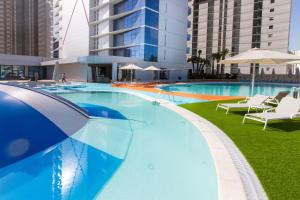 a large blue swimming pool with chairs and umbrellas at ESTIMAR Calpe Suitopia in Calpe
