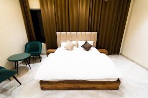 a bedroom with a white bed and two chairs at Dyal Resorts in Phagwāra