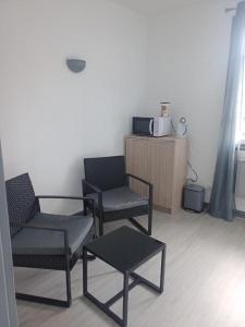 una stanza con tre sedie, un tavolo e un microonde di Les chambres du Montagut a Saint-Sauveur-de-Montagut