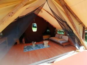a tent with a couch and a table in it at Lodge Robinson aux Nuits Insolites d'Argoumbat in Beaumont-de-Lomagne +6 photos