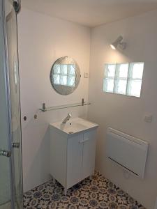 une salle de bains blanche avec un lavabo et un miroir dans l'établissement Le Roi des chats, gîte proche de Beauval et des châteaux, à Mareuil-sur-Cher